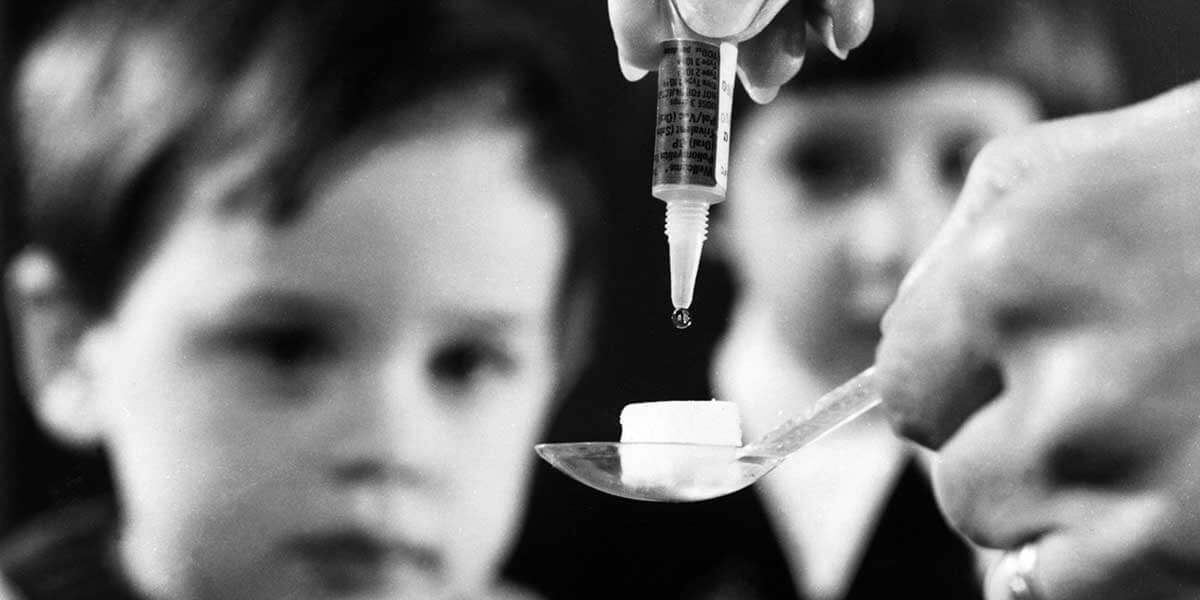 Black and white photo of polio vaccine dropped on to sugar lump for child patient