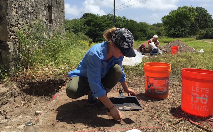 Woman kneeling down and digging for artifacts