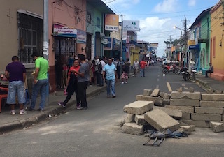People standing in street with broken concrete nearby
